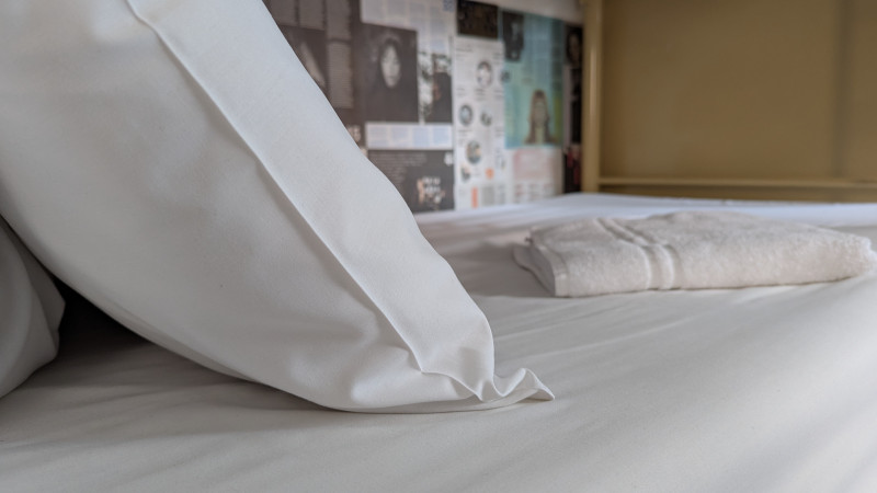 Fresh sheets and a folded towel on a made-up bed